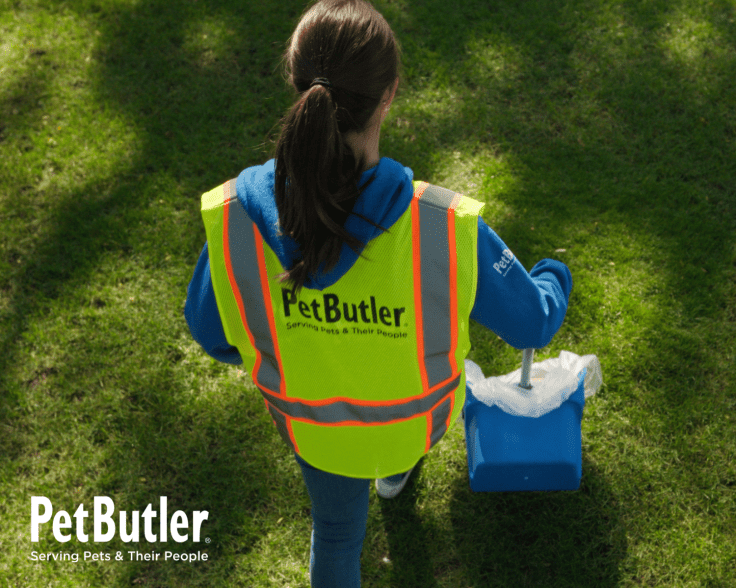 Pet Butler professional scooping dog waste in a customer’s yard.
