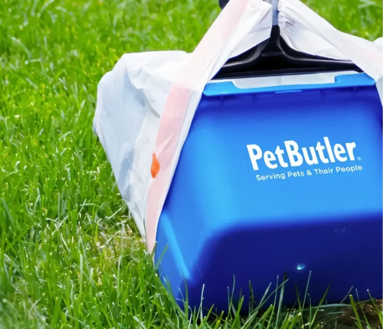 Pet Butler logoed blue bucket with a handle on the grass.