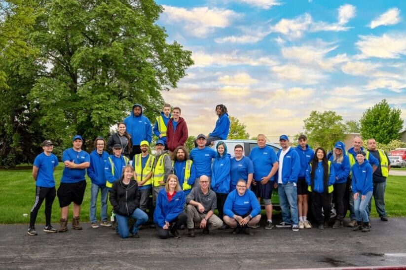 Team Photo of several Pet Butler employees smiling and posing in front of a Pet Butler vehicle in blue branded clothing