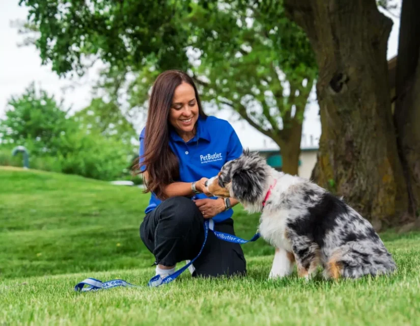 Rosemarie Richardson, owner of Pet Butler Chadds Ford PA, is posing with a dog while on a walk on a sunny day