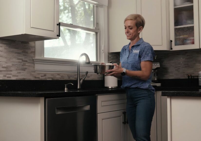 Pet Care technician walking with dog's water bowl